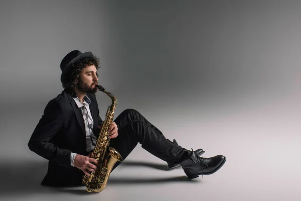 Yakışıklı jazzman katta otururken saksafon oynamaya — Stok fotoğraf