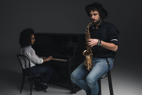 man playing saxophone while his partner playing piano blurred on background