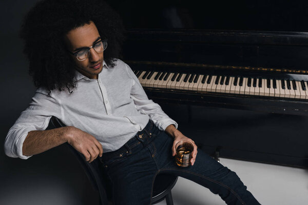 african american musician with glass of whiskey in front of piano