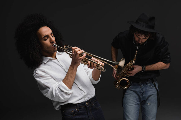 duet of musicians playing trumpet and sax on black