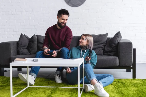 Sorrindo Casal Tatuado Jogando Videogame Olhando Para Outro — Fotografia de Stock