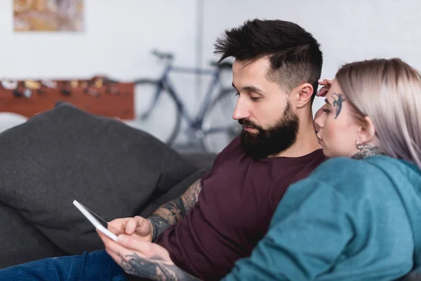 Τατουάζ Ζευγάρι Ψάχνει Στο Tablet Στον Καναπέ Στο Σπίτι — Δωρεάν Φωτογραφία