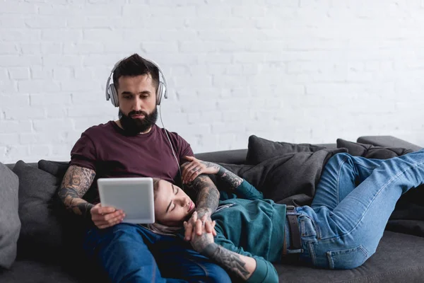 Tatuado Namorada Dormindo Namorado Ouvir Música Com Tablet Sofá — Fotografia de Stock