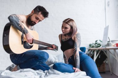 dövmeli erkek kız yatak odasında için gitar çalmak