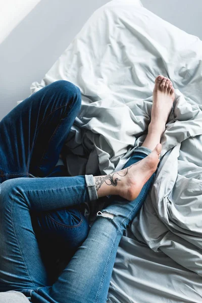 自宅のベッドで横になっている入れ墨のカップルの画像をトリミング — ストック写真