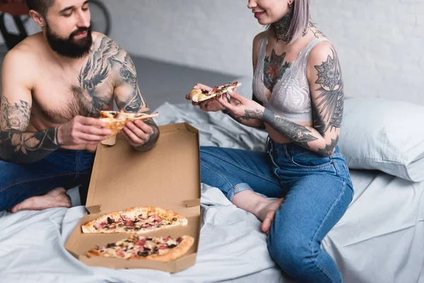 家でピザを食べる入れ墨のカップルの画像をトリミング — ストック写真
