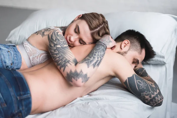 ベッドで寝ている上半身裸の入れ墨のカップル — ストック写真