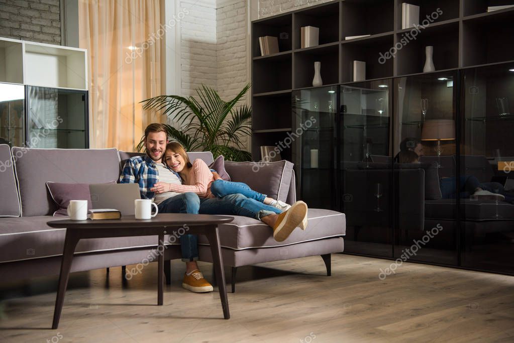 Couple having fun while watching laptop in modern living room
