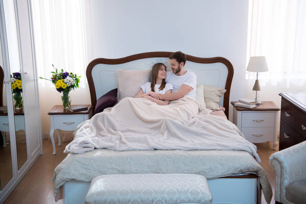 Happy couple hugging in bedroom with design interior