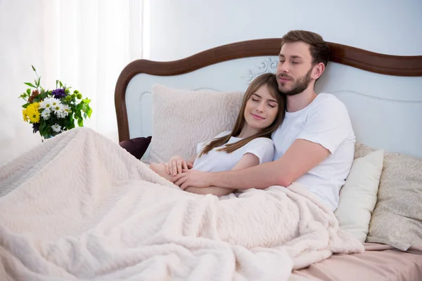 Jovem Casal Abraçando Cama Com Olhos Fechados Quarto Moderno — Fotografia de Stock