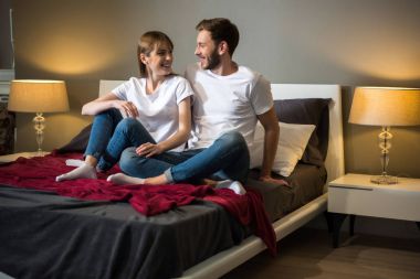 Mutlu genç çift yatakta rahat modern yatak odası oturma