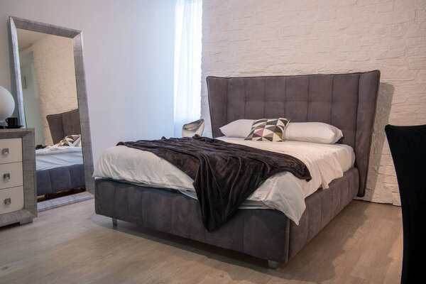 Интерьер современной спальни с кроватью и зеркалом
