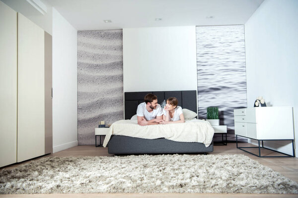 Young couple lying in bedroom with modern interior