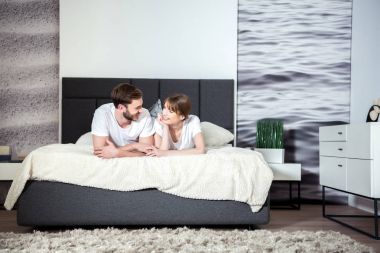 Mutlu çift yalan ve rahat modern yatak odasında konuşuyor