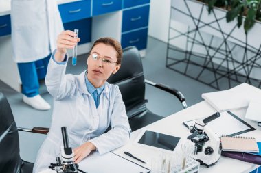 seçici odak kadın araştırmacı reaktif ile tüp elinde laboratuarında meslektaşı ile bakıyor