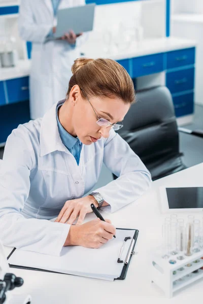 Selective Focus Female Scientist Making Notes Notepad Colleague Lab — Stock Photo, Image