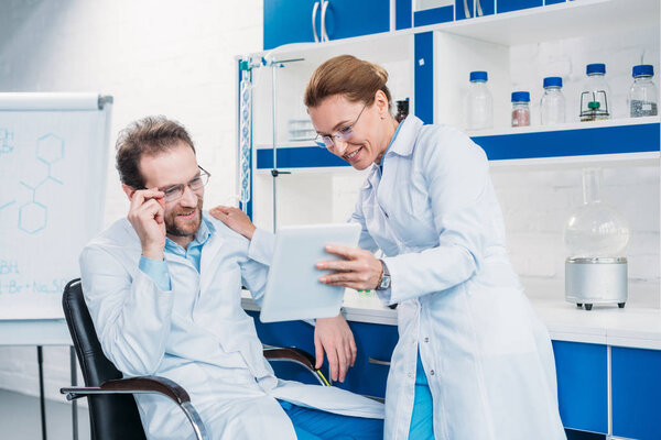 portrait of scientific researchers in lab coats using digital tablet together in laboratory