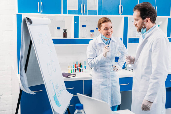 scientist in white coats near board for notes having discussion during work in lab
