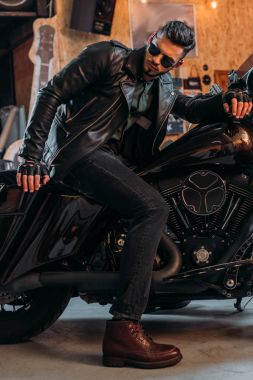 şık giyim motosiklet garajda otururken yakışıklı genç