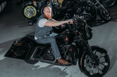 Bisiklet Garage ve kameraya bakarak şık genç adamın yüksek açılı görünüş
