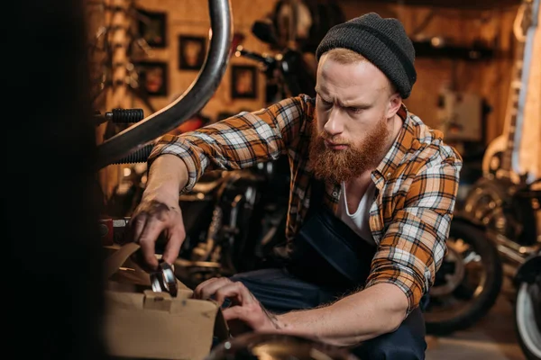 Stilig Cykel Reparation Station Arbetare Försöker Hitta Detaljer Låda Garage — Gratis stockfoto