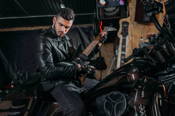 Jovem Bonito Tocando Guitarra Enquanto Sentado Bicicleta Garagem — Fotografia de Stock