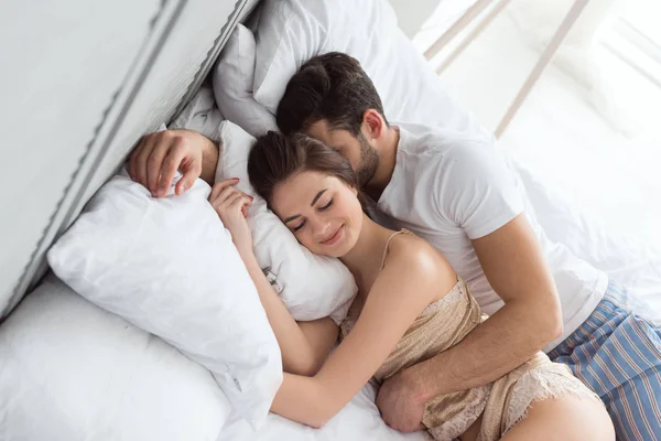 穿着睡衣的年轻夫妇一起睡在床上 — 图库照片