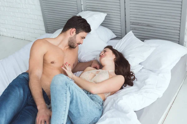 Sexy Jovem Casal Jeans Olhando Para Outro Enquanto Deitado Cama — Fotografia de Stock