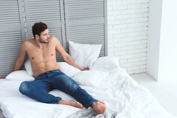 Genç Çekici Adam Yatakta Yatarken Kot Pantolon — Stok fotoğraf