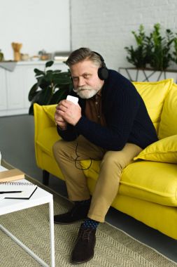 gülümseyen kıdemli yakışıklı smartphone ile müzik dinlerken kulaklık       