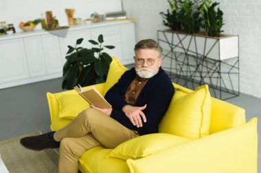 kanepe ve okuma kitabı üzerinde oturan gözlük üst düzey insanın yüksek açılı görünüş