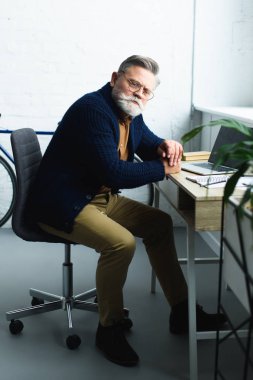 Komuta sizde dizüstü kullanarak ve kameraya bakarak gözlük sakallı 