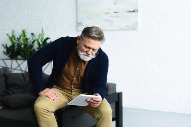 kanepede oturan ve evde dijital tablet kullanma yakışıklı sakallı komuta sizde