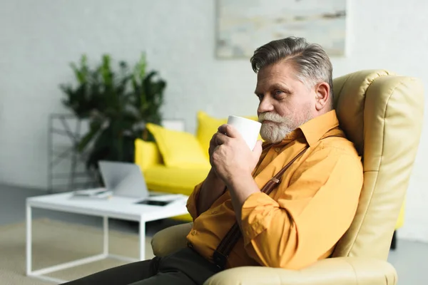 Smiling Bearded Senior Man Drinking Coffee Cup While Sitting Armchair — Stock Photo, Image