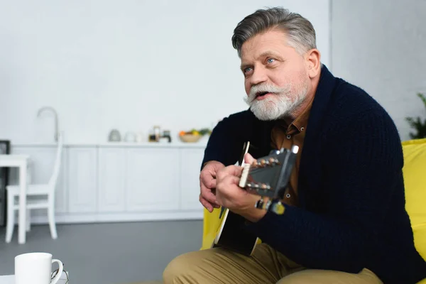 Handsome Bearded Senior Man Playing Guitar Looking Away Home — Stock Photo, Image