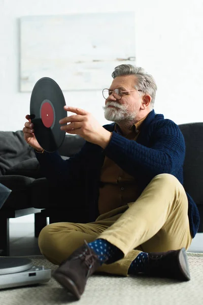 Sorrindo Elegante Homem Sênior Óculos Segurando Recorde Vinil Enquanto Sentado — Fotografia de Stock