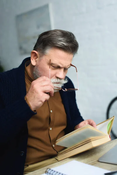 Homem Idoso Barbudo Ajustando Óculos Livro Leitura Casa — Fotografia de Stock