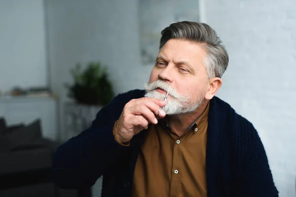 Przystojny Mężczyzna Senior Przycinania Wąsów Nożyczkami Domu — Zdjęcie stockowe