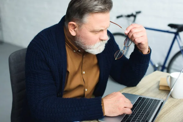 Koncentrerad Senior Mannen Håller Glasögon Och Använder Bärbar Dator — Stockfoto