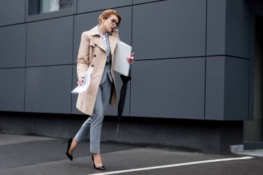 iş kadını sokakta yürürken smartphone üzerinde konuşurken belgelerle