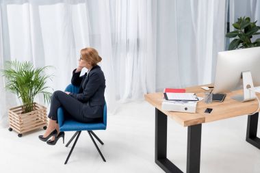 office sandalyede oturan takım elbiseli dalgın işkadını