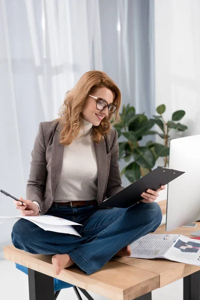 Mujer Negocios Sonriente Gafas Haciendo Papeleo Mientras Está Sentada Mesa —  Fotos de Stock