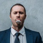 Cropped shot of businessman with mouth full of cigarettes