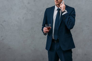 cropped shot of businessman with glass of whiskey talking by phone clipart