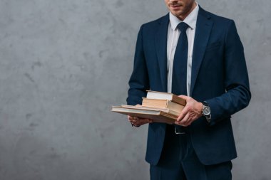 Beton duvar önünde, kitap yığını tutan işadamı kadeh kırpılmış