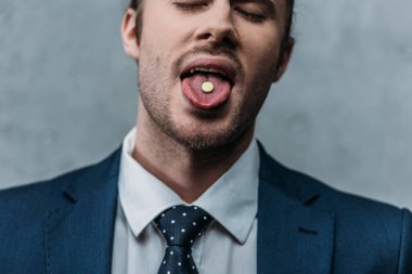 close-up portrait of addicted businessman sticking out tongue with mdma pill clipart