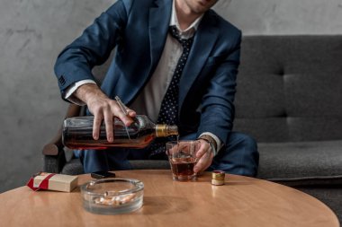 kanepede otururken viski içme alkol bağımlısı işadamı kadeh kırpılmış