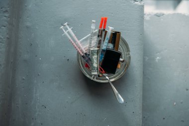 top view of can with heroin syringes and various objects clipart