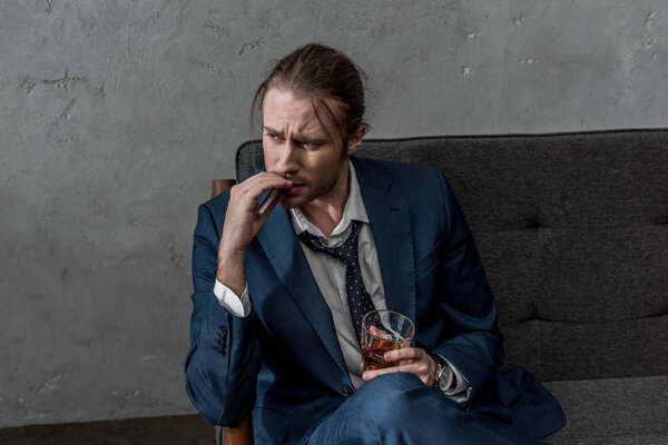 drunk alcohol addicted businessman with glass of whiskey smoking cigarette