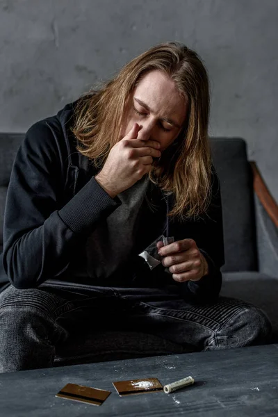 ソファに座ってのコカインのスニッフィング中毒の男 — ストック写真